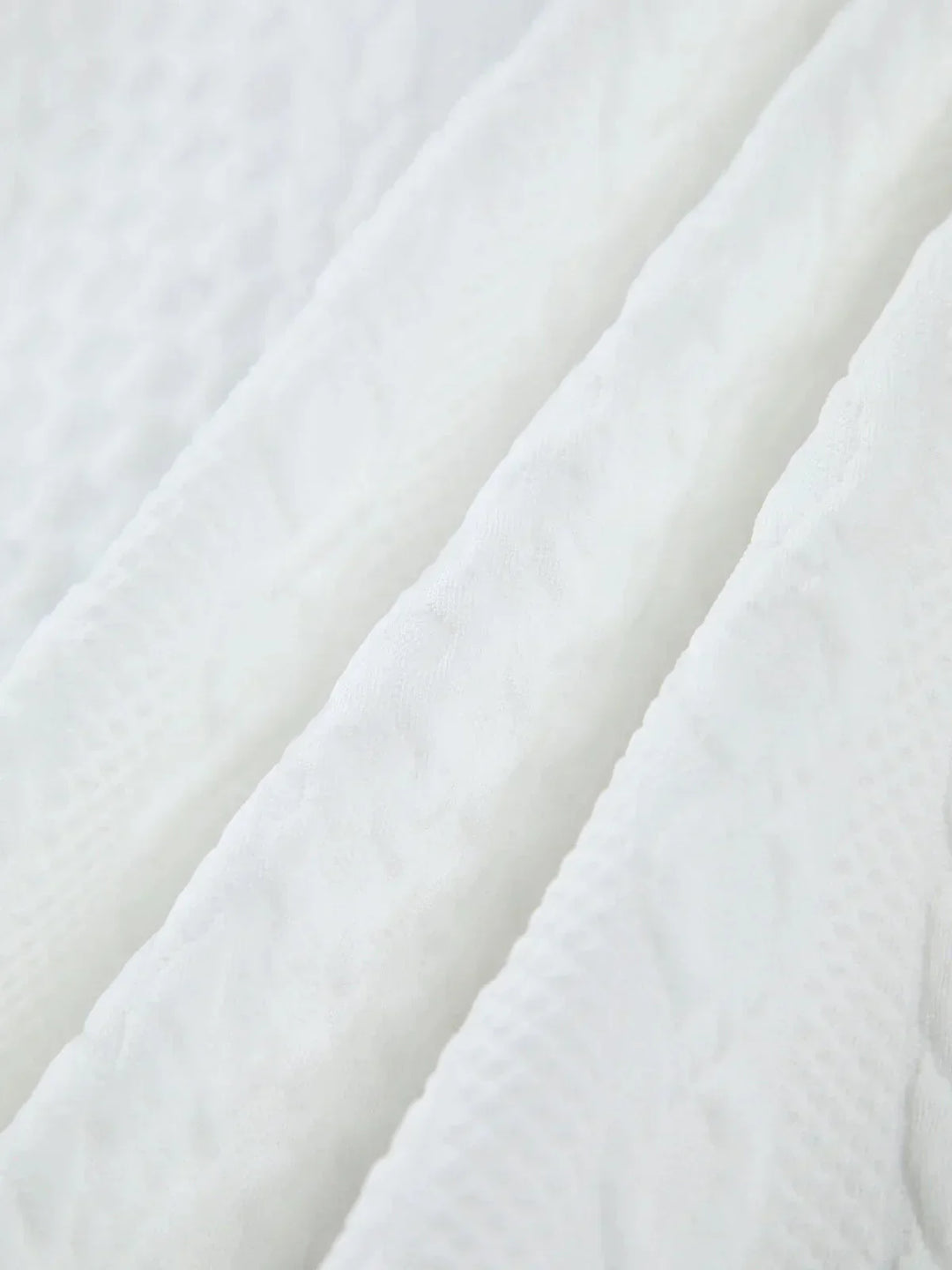 Blouse femme blanche en tissu texturé avec manches sculptées, idéale pour une allure élégante et moderne.
