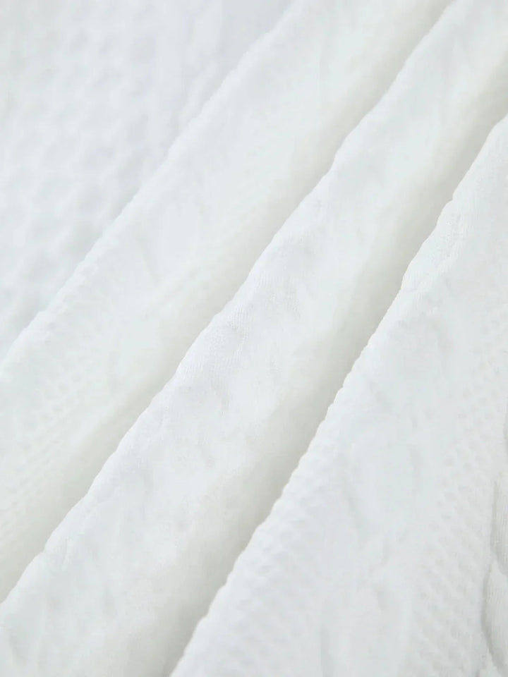 Blouse femme blanche en tissu texturé avec manches sculptées, idéale pour une allure élégante et moderne.