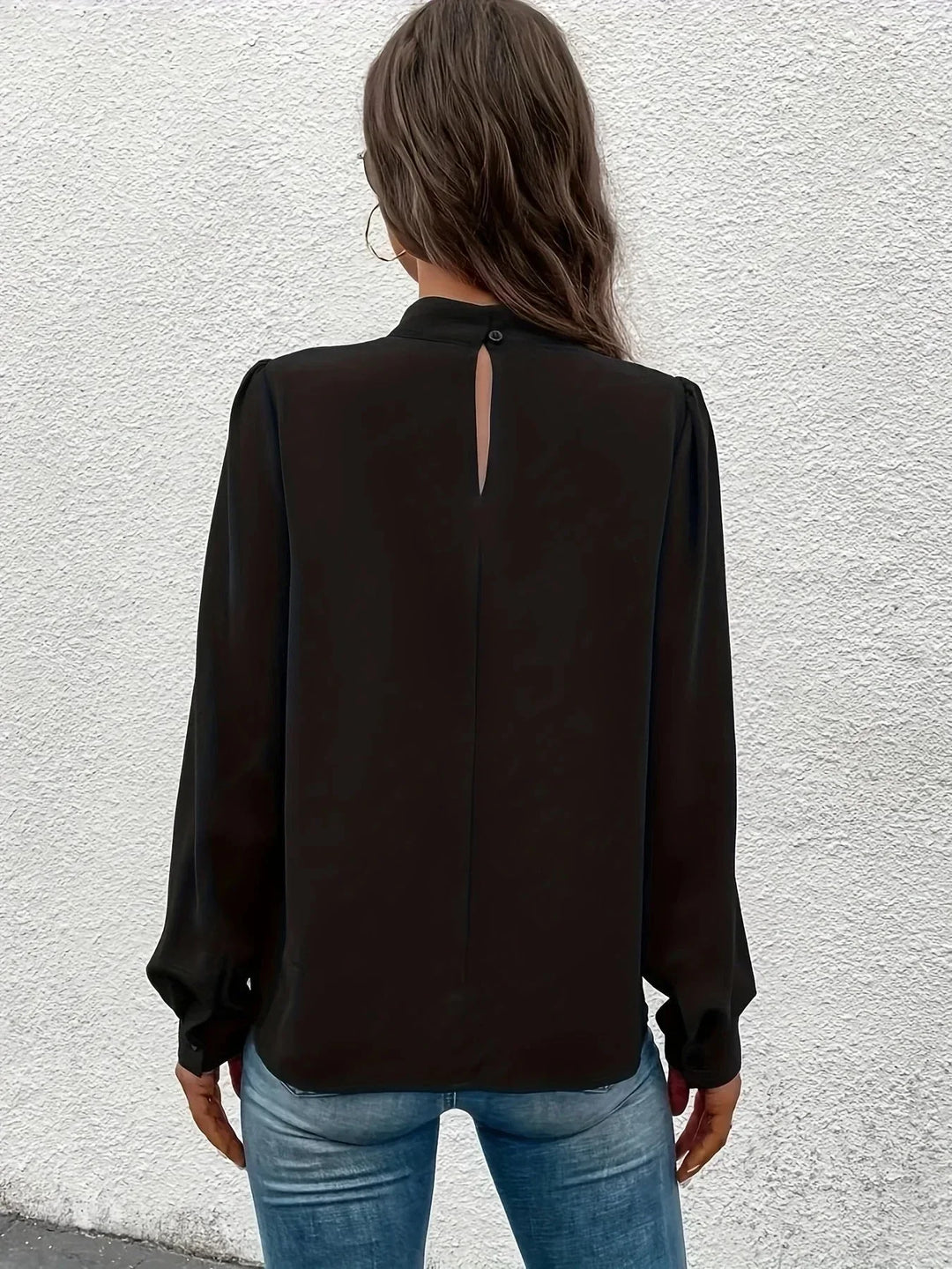 Haut noir à manches longues pour femme, coupe élégante, en tissu léger avec des détails raffinés.