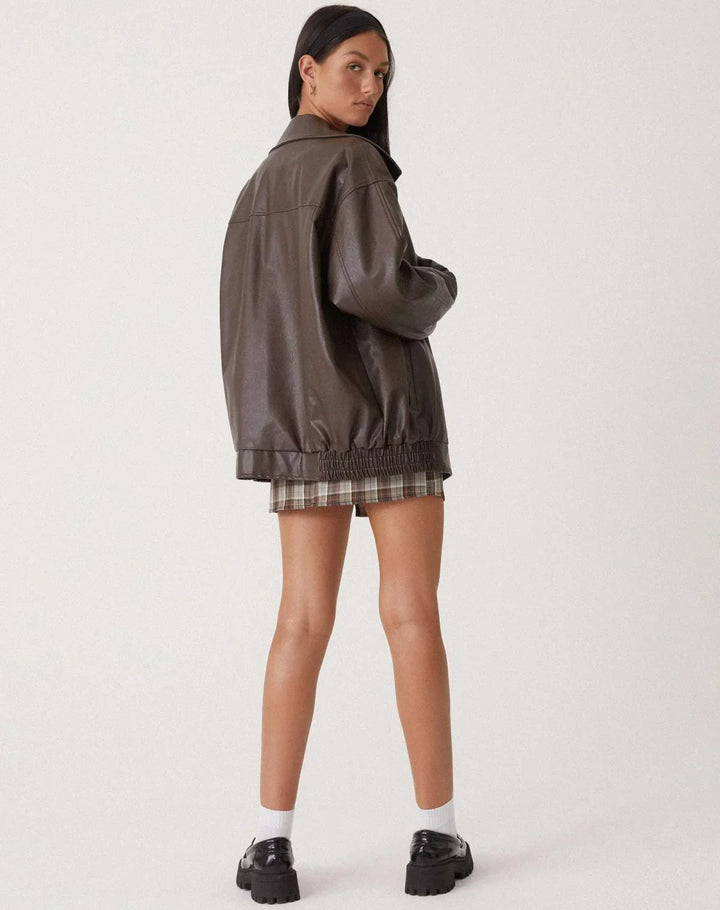 Blouson femme motard en similicuir marron, avec fermeture éclair asymétrique et deux poches latérales.