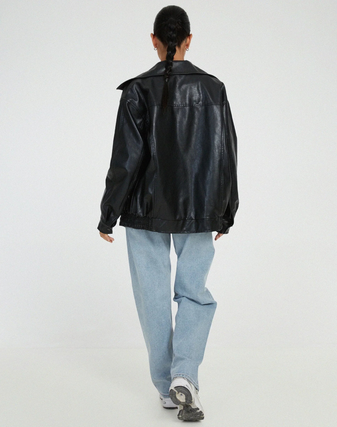 Blouson femme noir en similicuir, style motard, avec fermeture éclair et deux poches latérales.