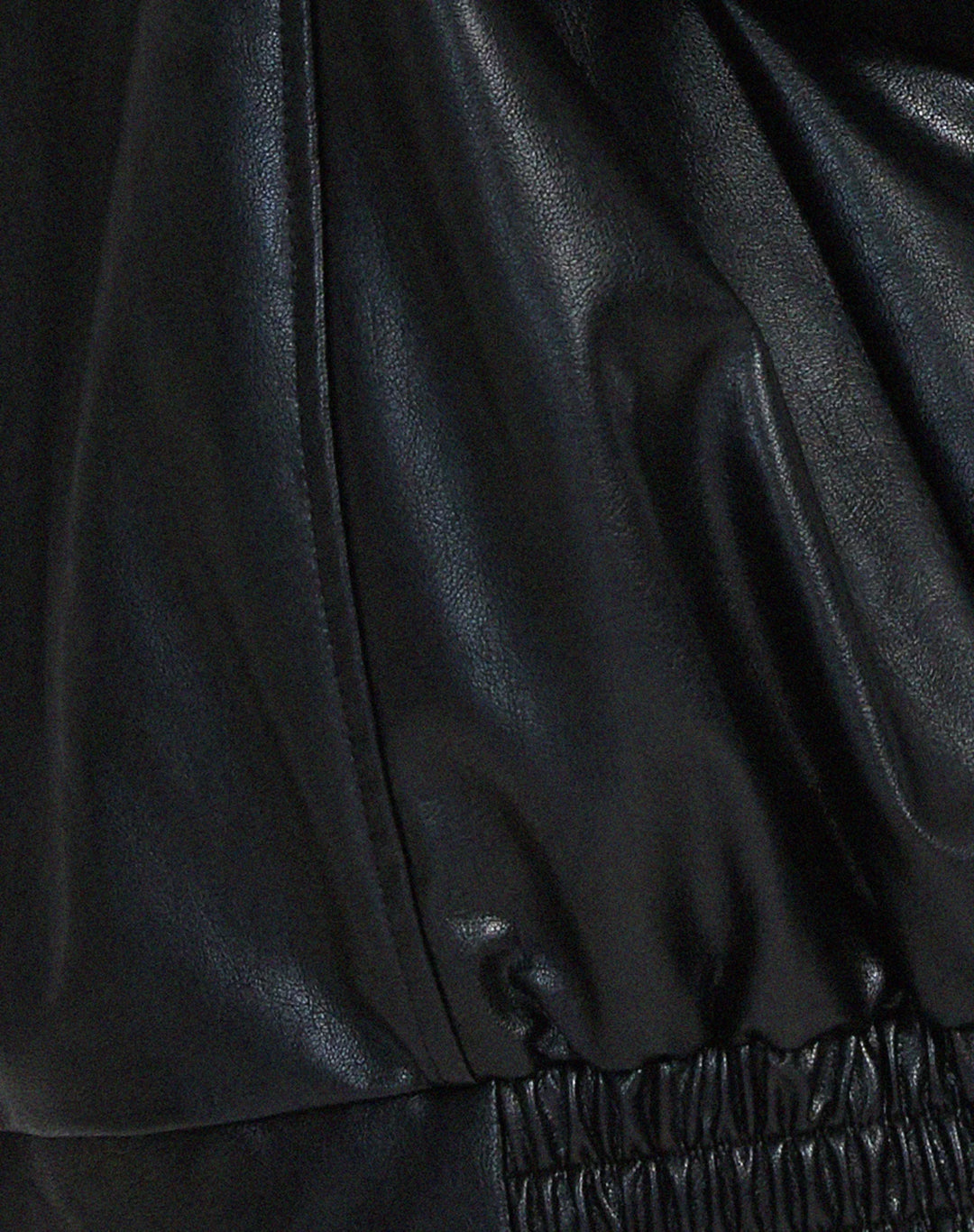 Blouson femme noir en similicuir, style motard, avec zips et col rabattu.