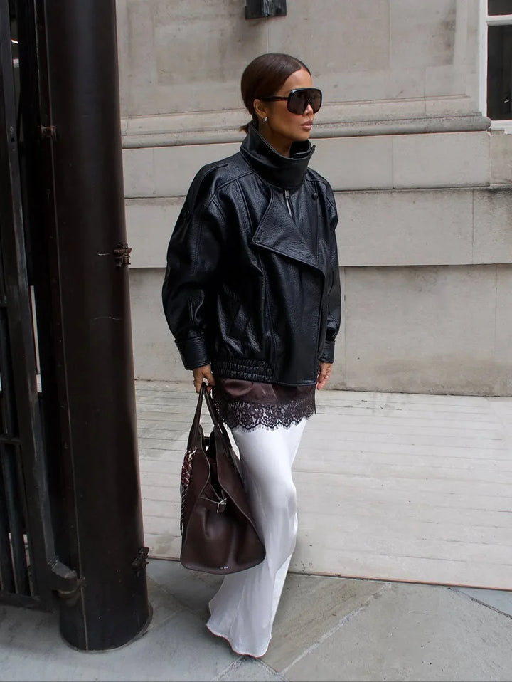 Blouson noir pour femme en matériau résistant, col montant et design moderne et minimaliste.