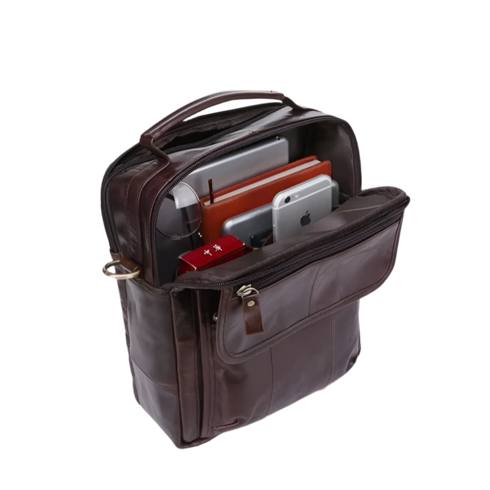 Zaino in pelle marrone con scomparti aperti, contenente laptop, tablet e smartphone. Ideale per lavoro e viaggio. Accessorio elegante e funzionale.
