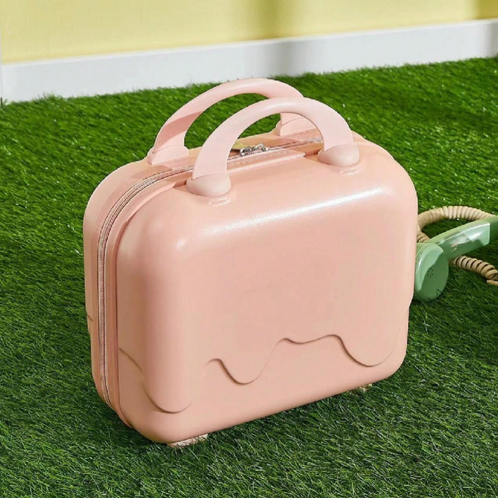 Valigia rosa a forma di gelato su prato verde, design moderno e compatto, ideale per viaggi brevi. Accessorio da viaggio elegante e funzionale.