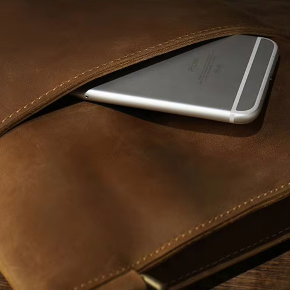 Smartphone grigio in una custodia di pelle marrone, design elegante, accessorio tecnologico, protezione dispositivo mobile, stile moderno.