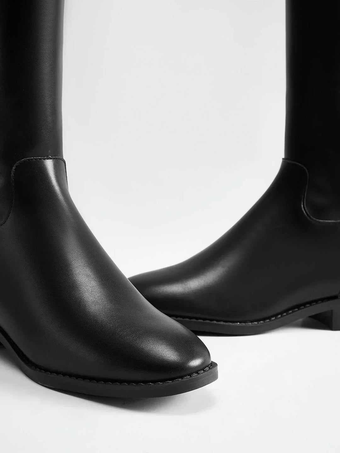 Bottes noires équestres en cuir avec boucle décorative sur le côté. Construction élégante et robuste.