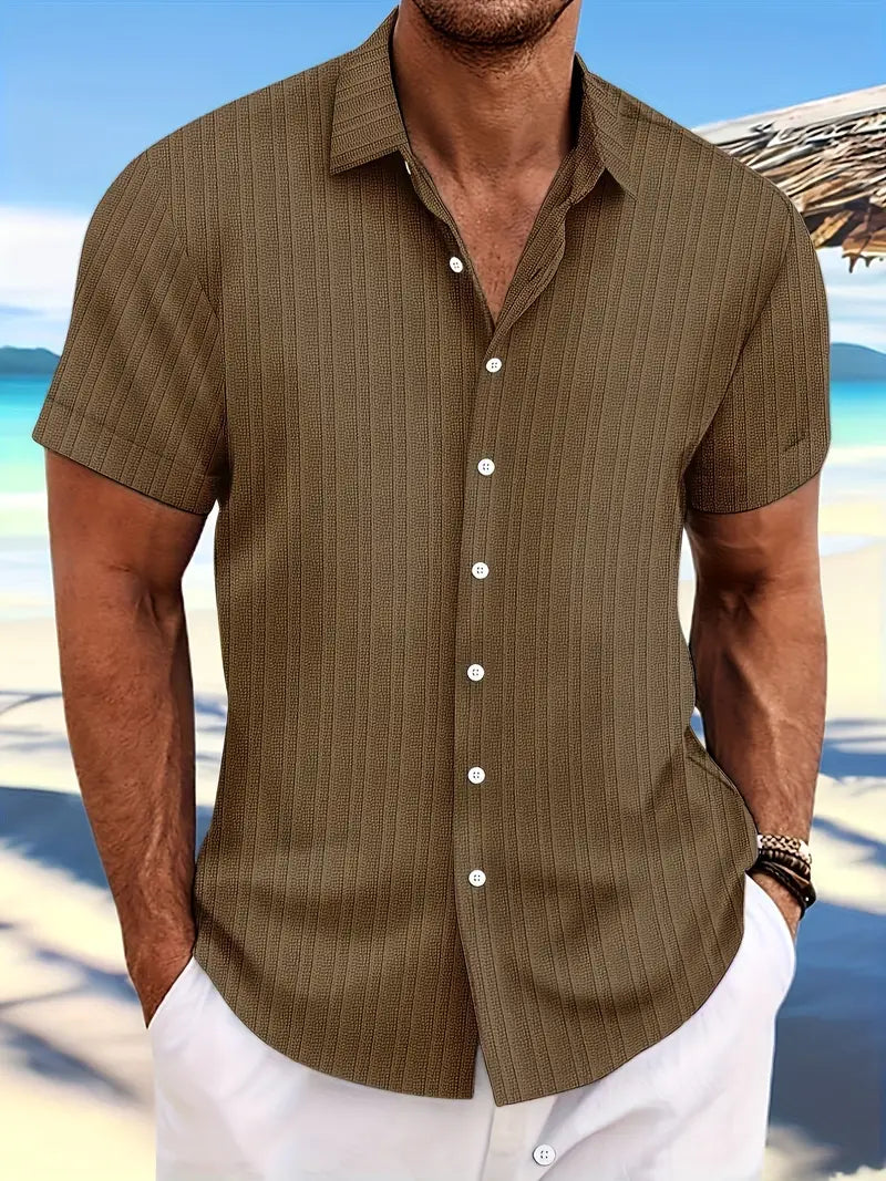 Camicia estiva da uomo a righe marroni, maniche corte, sfondo spiaggia, stile casual elegante, perfetta per vacanze al mare e look estivo.