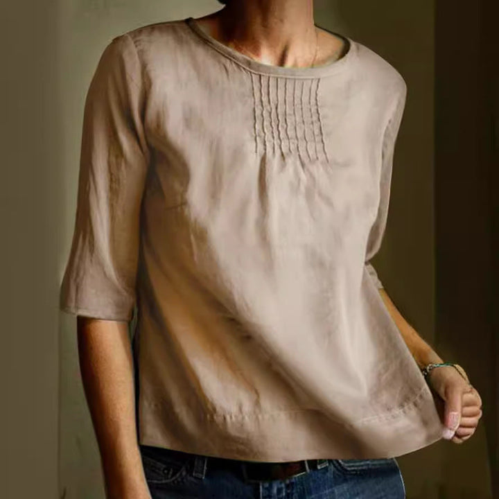 Blusa beige da donna in cotone, maniche a tre quarti, scollo rotondo, dettagli plissettati sul petto, stile casual elegante.