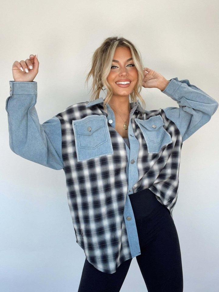 Donna sorridente con camicia a quadri bianca e nera, maniche denim, sfondo bianco. Moda casual, stile autunnale, abbigliamento femminile trendy.