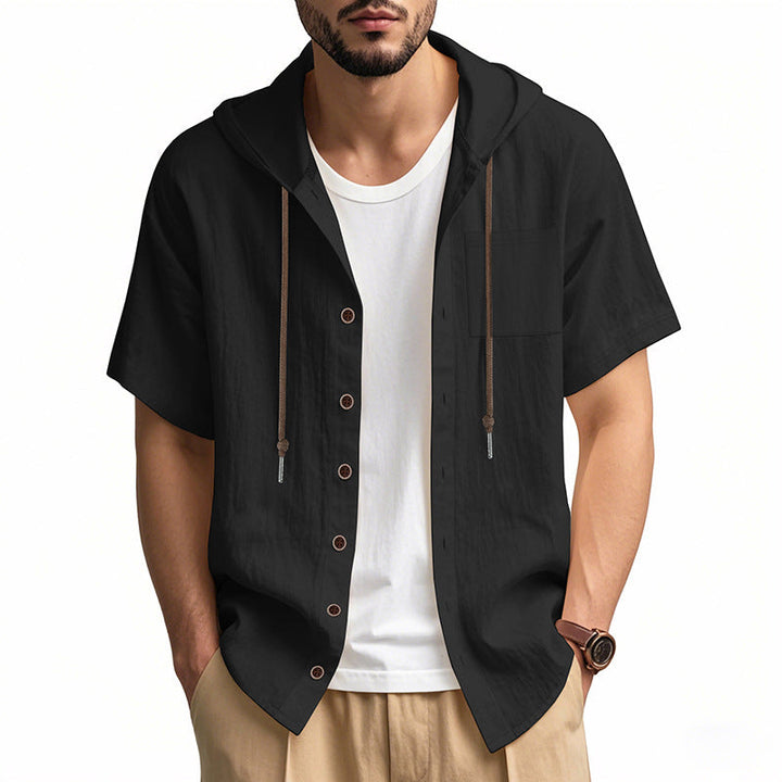 Camicia uomo nera con cappuccio, maniche corte, bottoni frontali, indossata sopra t-shirt bianca. Stile casual, moda estiva maschile.
