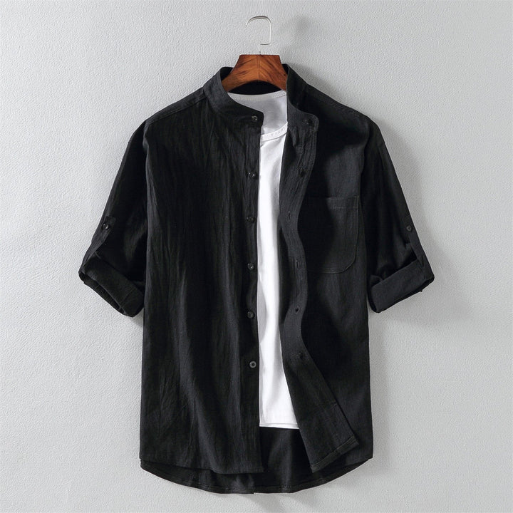 Camicia nera da uomo in cotone, maniche lunghe arrotolate, colletto alla coreana, abbinata a t-shirt bianca. Elegante e casual.