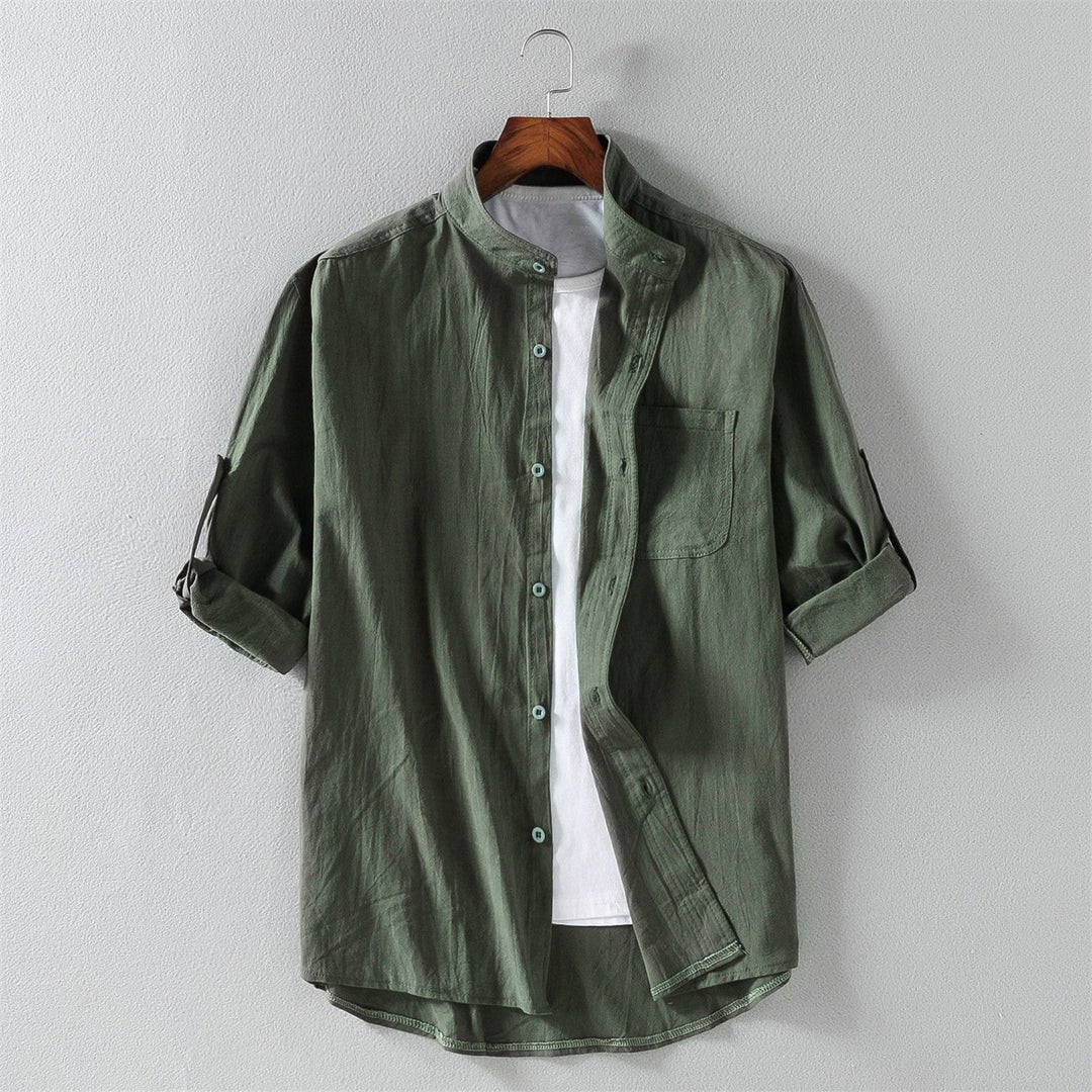 Camicia verde militare da uomo con colletto alla coreana, maniche lunghe arrotolate, taschino frontale, su gruccia. Stile casual elegante.