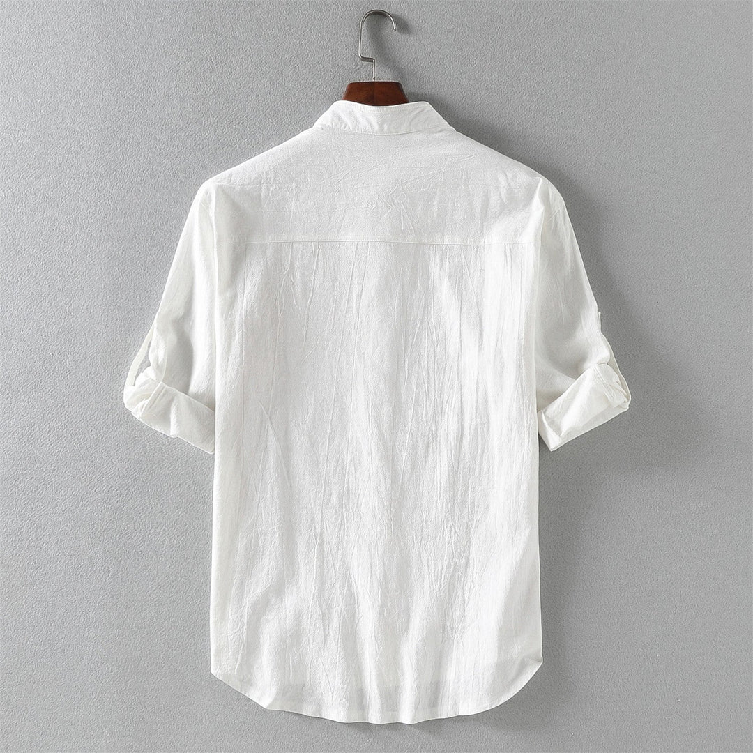Camicia bianca da uomo in cotone, maniche lunghe arrotolate, appesa su gruccia. Design classico, ideale per look casual ed eleganti.