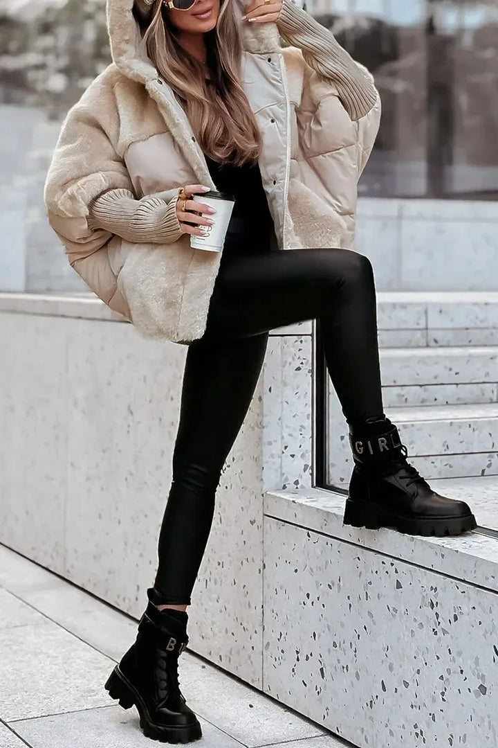 Cape d'hiver matelassée noire avec capuche et col en fausse fourrure, conçue pour les jours froids.