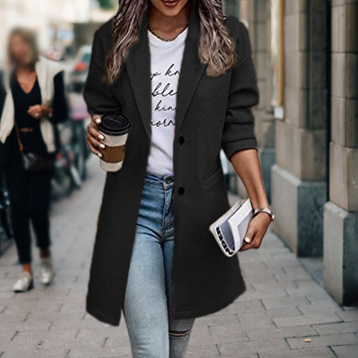 Donna con cappotto nero elegante, jeans, maglietta bianca, tiene caffè e borsa. Moda autunnale urbana, abbigliamento casual chic.