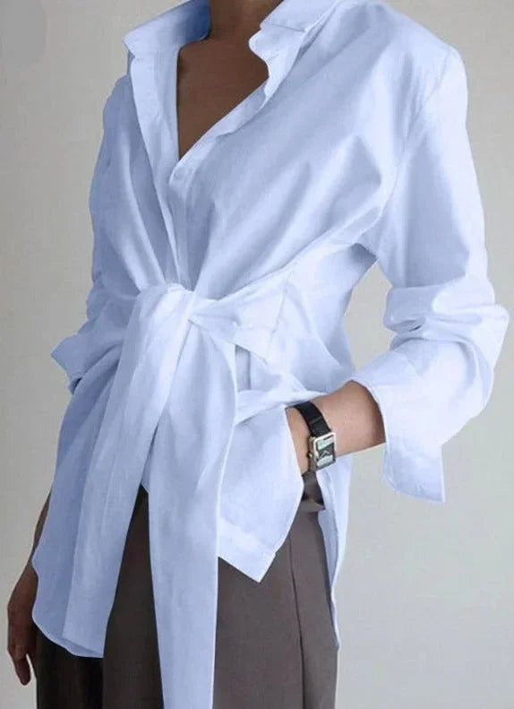 Chemise blanche pour femme, ajustable avec ceinture nouée, en tissu léger et au design intemporel.