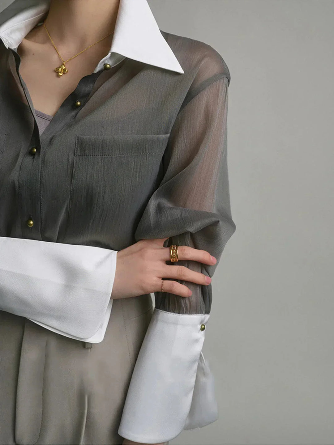 Chemisier transparent en chiffon, avec boutons délicats et col élégant pour un look chic et féminin.