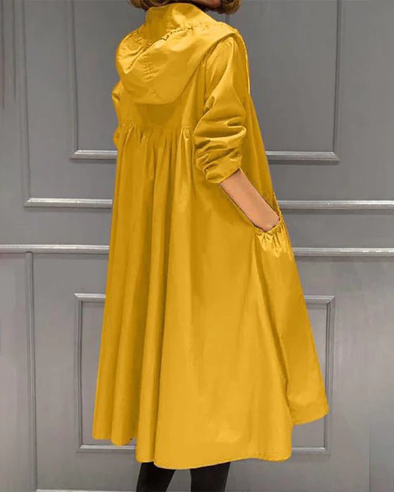 Cappotto giallo con cappuccio, design ampio e tasche laterali, moda autunnale donna, elegante e casual, perfetto per giornate fresche.