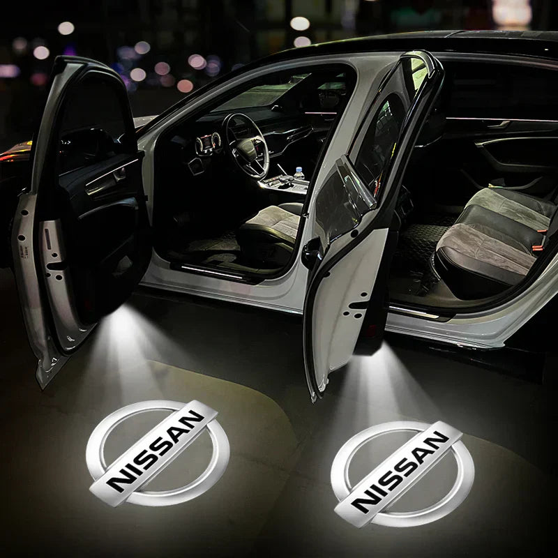 Auto con portiere aperte e logo Nissan proiettato a terra, interni visibili. Illuminazione LED, design moderno. Accessori auto, personalizzazione.