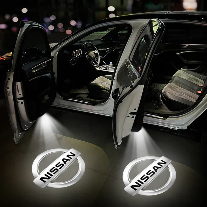 Auto con portiere aperte e logo Nissan proiettato a terra, interni visibili. Illuminazione LED, design moderno. Accessori auto, personalizzazione.