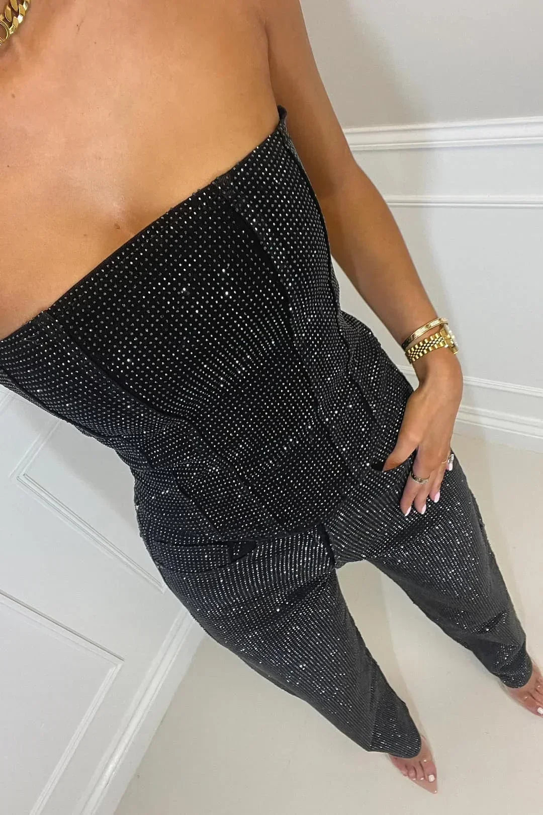 Combinaison noire femme bustier avec jambes larges, en tissu léger, adaptée pour des soirées élégantes.