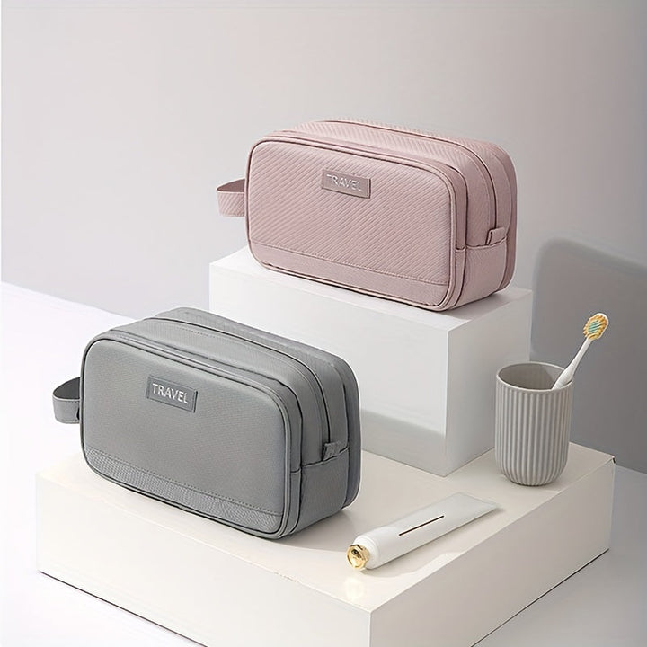 Due beauty case da viaggio in tessuto, uno grigio e uno rosa, su piedistalli bianchi. Include spazzolino e dentifricio. Accessori eleganti e pratici.