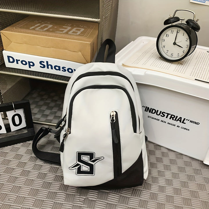 Zaino bianco e nero con logo "S", tasche multiple, su pavimento a scacchi. Orologio nero e scatola industriale sullo sfondo.
