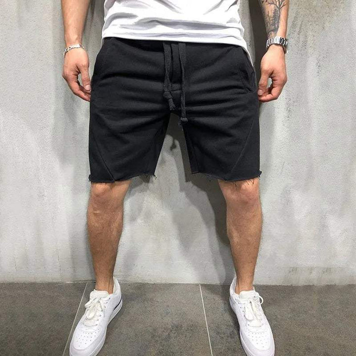 Shorts neri da uomo in cotone, stile casual, con coulisse, indossati con t-shirt bianca e sneakers bianche. Ideali per moda estiva e tempo libero.