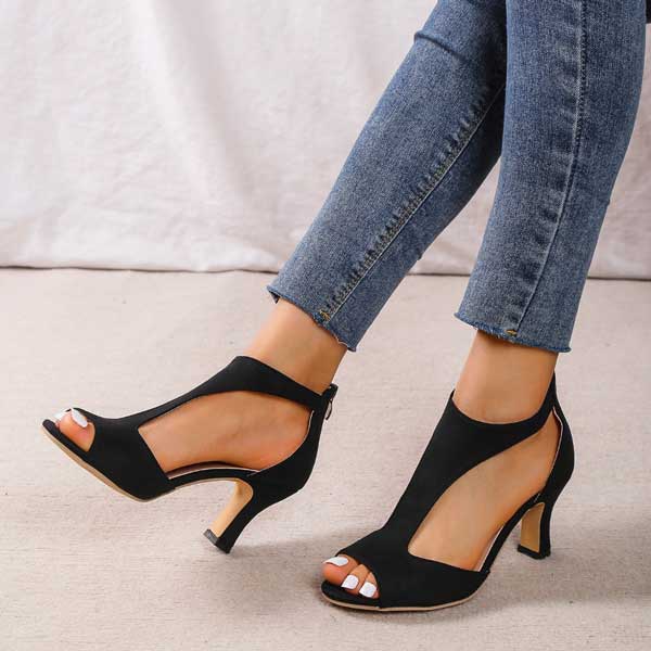 Scarpe col tacco nere eleganti con design aperto, indossate con jeans aderenti. Calzature moda donna, stile moderno e chic.