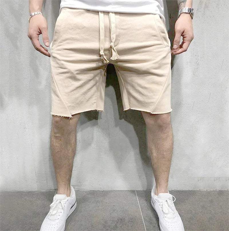 Pantaloncini beige da uomo, casual, in cotone, con coulisse, indossati con scarpe da ginnastica bianche. Look estivo, moda maschile.