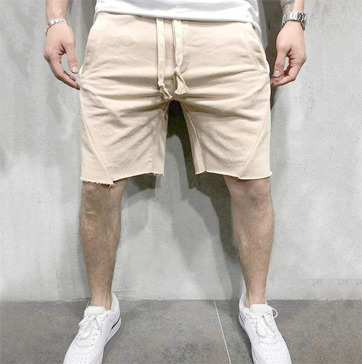 Pantaloncini beige da uomo, casual, in cotone, con coulisse, indossati con scarpe da ginnastica bianche. Look estivo, moda maschile.