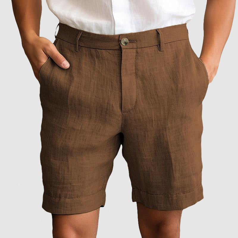 Pantaloncini uomo in lino marrone, tasche laterali, chiusura con bottone, stile casual estivo, abbinati a camicia bianca.