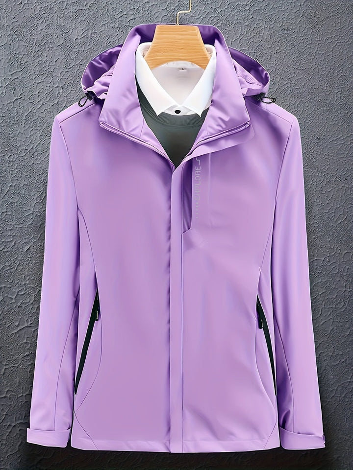 Giacca impermeabile viola da donna con cappuccio, chiusura a zip, tasche laterali, appesa su gruccia. Ideale per outdoor e sport.