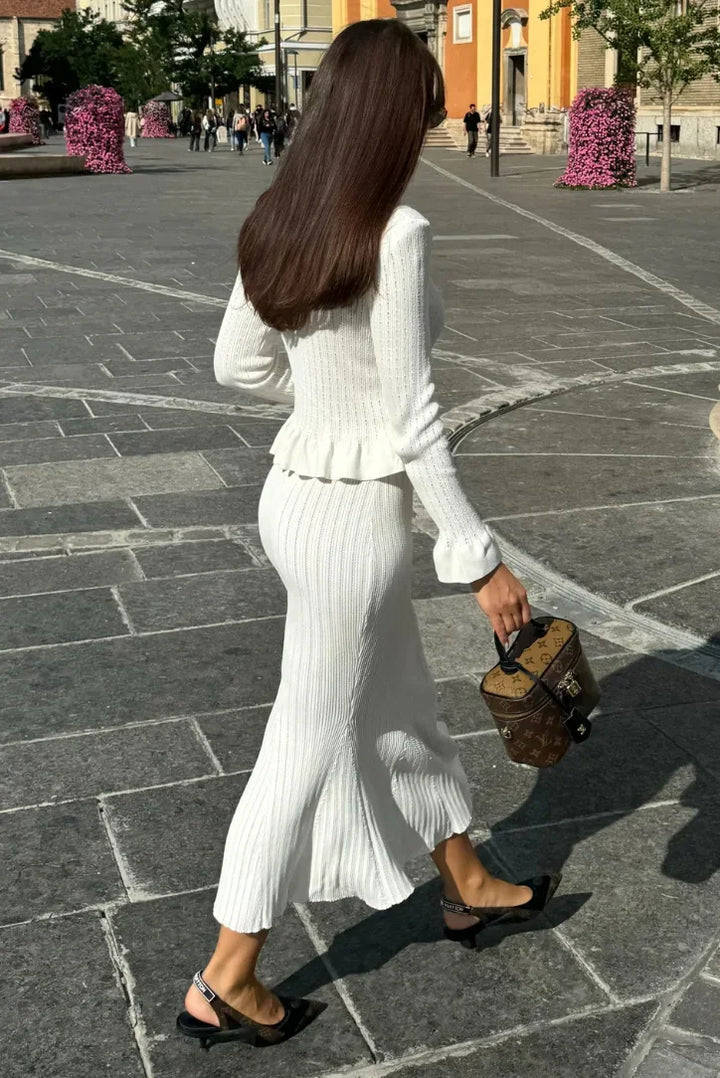 Ensemble femme ajusté en tissu doux, présentant un cardigan ouvert et une jupe mi-longue à la coupe élégante.