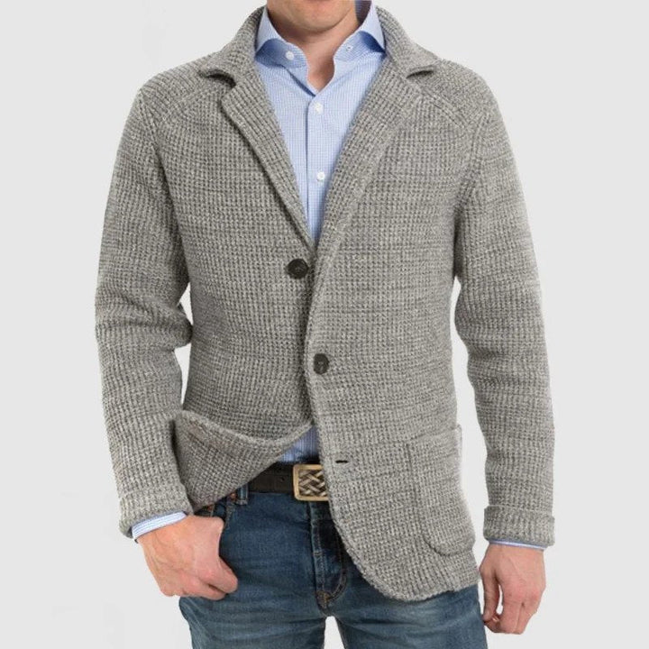Giacca cardigan uomo grigia in maglia, stile casual elegante, con bottoni e tasche frontali, indossata su camicia azzurra e jeans.