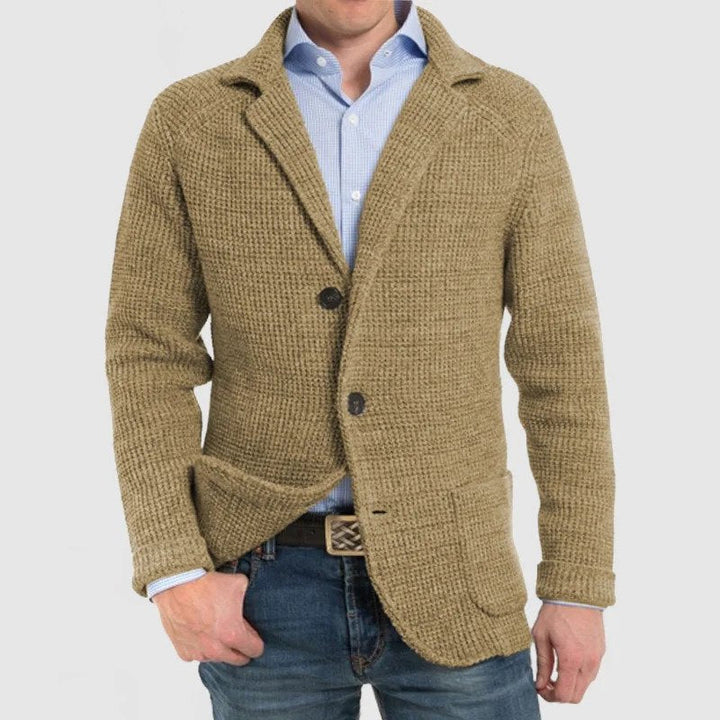 Giacca uomo beige in maglia, stile casual, con bottoni e tasche frontali, indossata su camicia azzurra e jeans. Moda maschile autunnale.