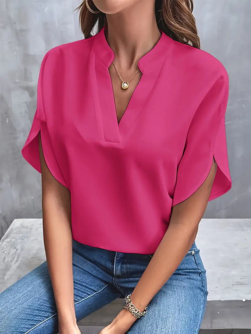 Blusa rosa fucsia elegante da donna, maniche corte, scollo a V, abbinata a jeans. Moda casual femminile, abbigliamento estivo trendy.