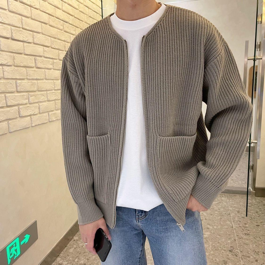Giacca cardigan uomo in maglia grigia, stile casual, con tasche frontali, indossata su t-shirt bianca e jeans. Moda autunnale maschile.