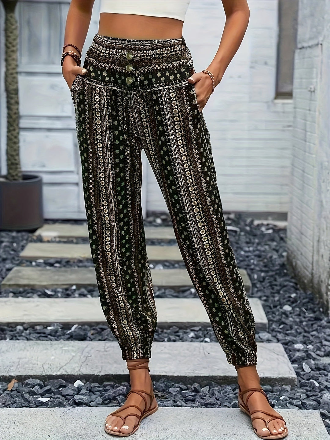 Pantaloni boho donna a vita alta, motivo etnico, tasche laterali, fondo elastico, stile casual estivo, indossati con sandali marroni.