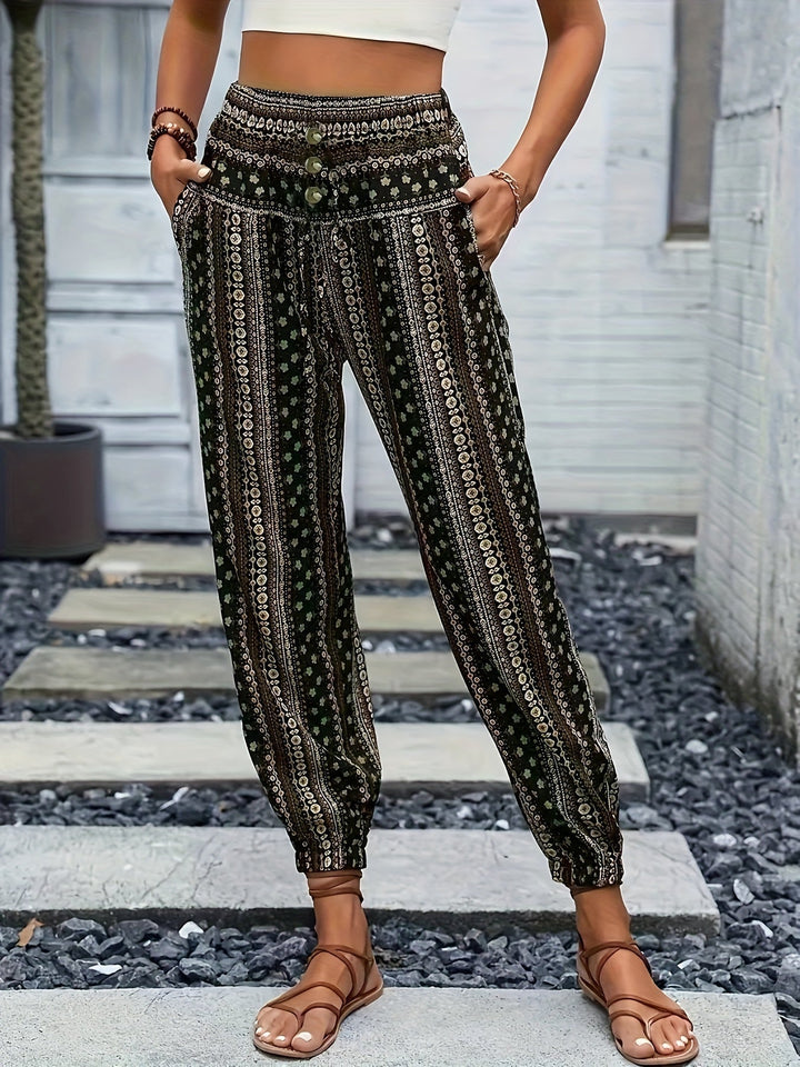 Pantaloni boho donna a vita alta, motivo etnico, tasche laterali, fondo elastico, stile casual estivo, indossati con sandali marroni.