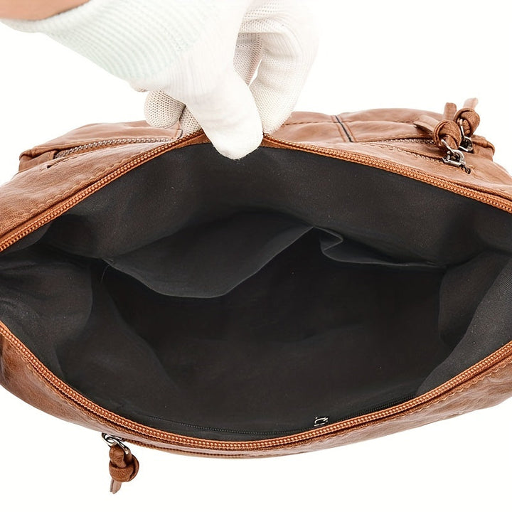 Borsa a tracolla in pelle marrone aperta, interno spazioso con fodera nera, chiusura a zip, design elegante e pratico per uso quotidiano.