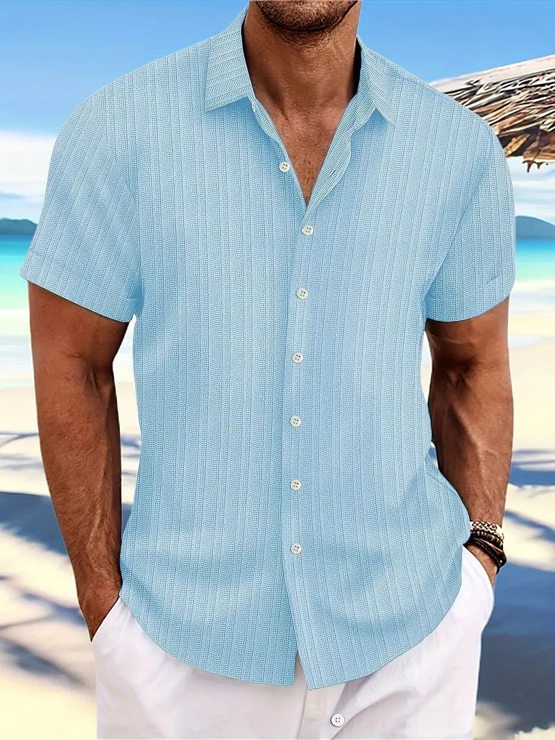 Camicia estiva uomo a righe azzurre, maniche corte, sfondo spiaggia tropicale. Moda casual, abbigliamento leggero, ideale per vacanze al mare.