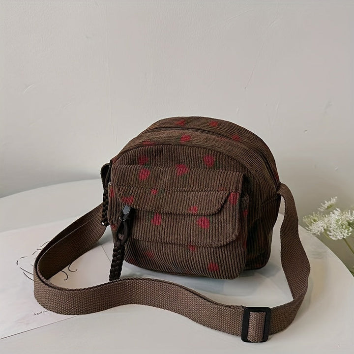 Borsa a tracolla marrone in velluto a coste con motivo a pois rossi, tasca frontale e chiusura a zip. Accessorio moda casual e versatile.
