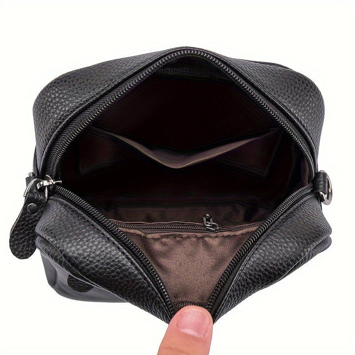 Borsello da uomo in pelle nera aperto, con scomparti interni visibili. Elegante e pratico, ideale per viaggi e uso quotidiano.