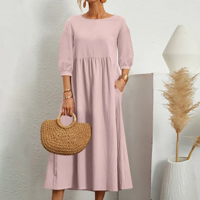 Abito lungo rosa donna, maniche a tre quarti, tasche laterali, borsa paglia intrecciata, sfondo bianco minimalista, moda estiva elegante.