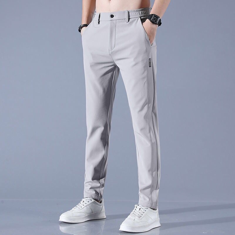 Pantaloni uomo grigi eleganti, vestibilità slim, con tasche laterali. Ideali per look casual e formali. Indossati con sneakers bianche.
