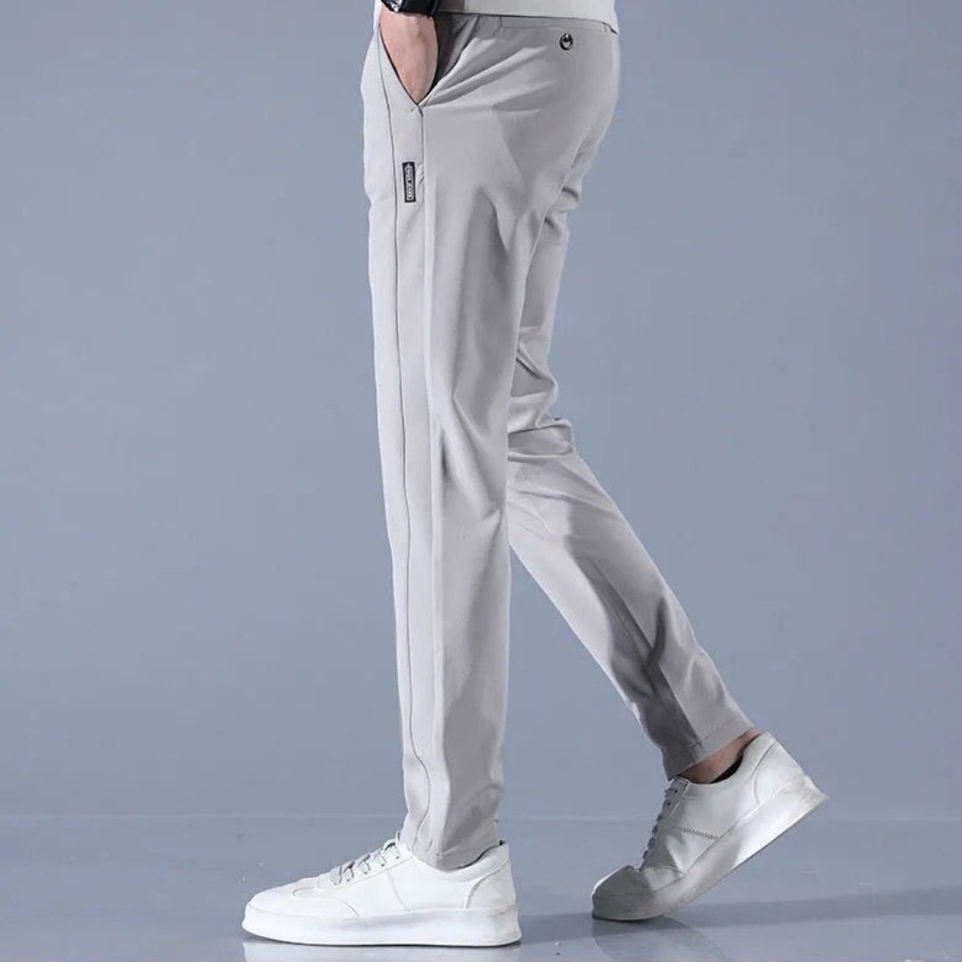 Pantaloni sportivi grigi da uomo, vestibilità slim, con tasche laterali, abbinati a scarpe da ginnastica bianche. Moda casual maschile.