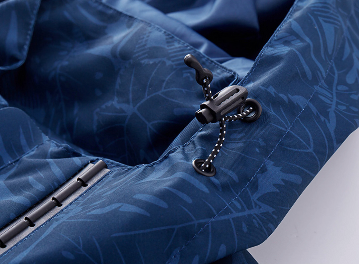 Giacca impermeabile blu con motivo foglie, chiusura a cordoncino regolabile e dettagli in plastica nera. Ideale per outdoor e sport.