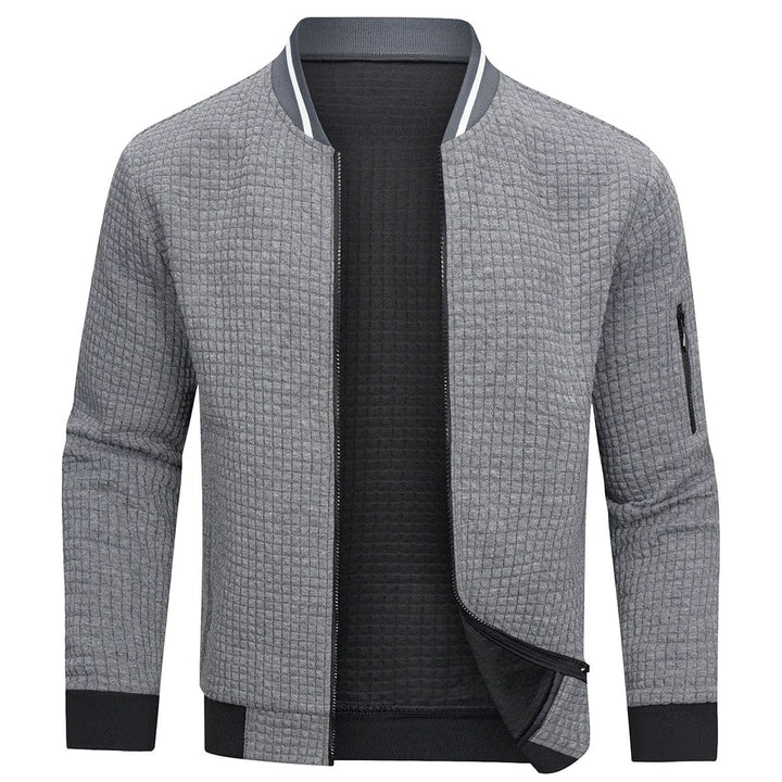 Giacca bomber uomo grigia, tessuto trapuntato, zip frontale, polsini e orlo a costine, tasca con zip sulla manica, stile casual elegante.